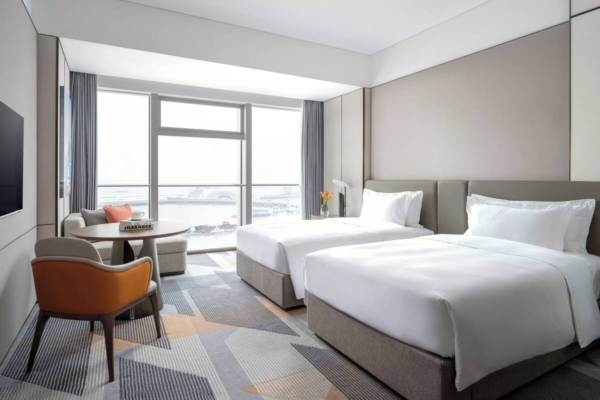 Une chambre d’hôtel avec deux lits, un canapé, une petite table et un téléviseur.