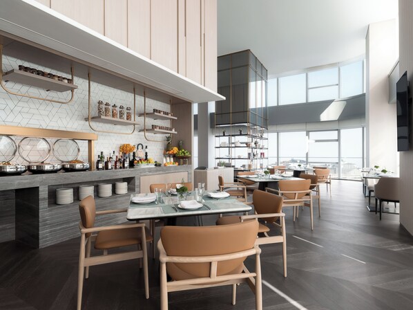 A modern dining area with a high ceiling, large windows, and a kitchen with open shelving. - Cordis Shanghai Seaworld (Shanghai)