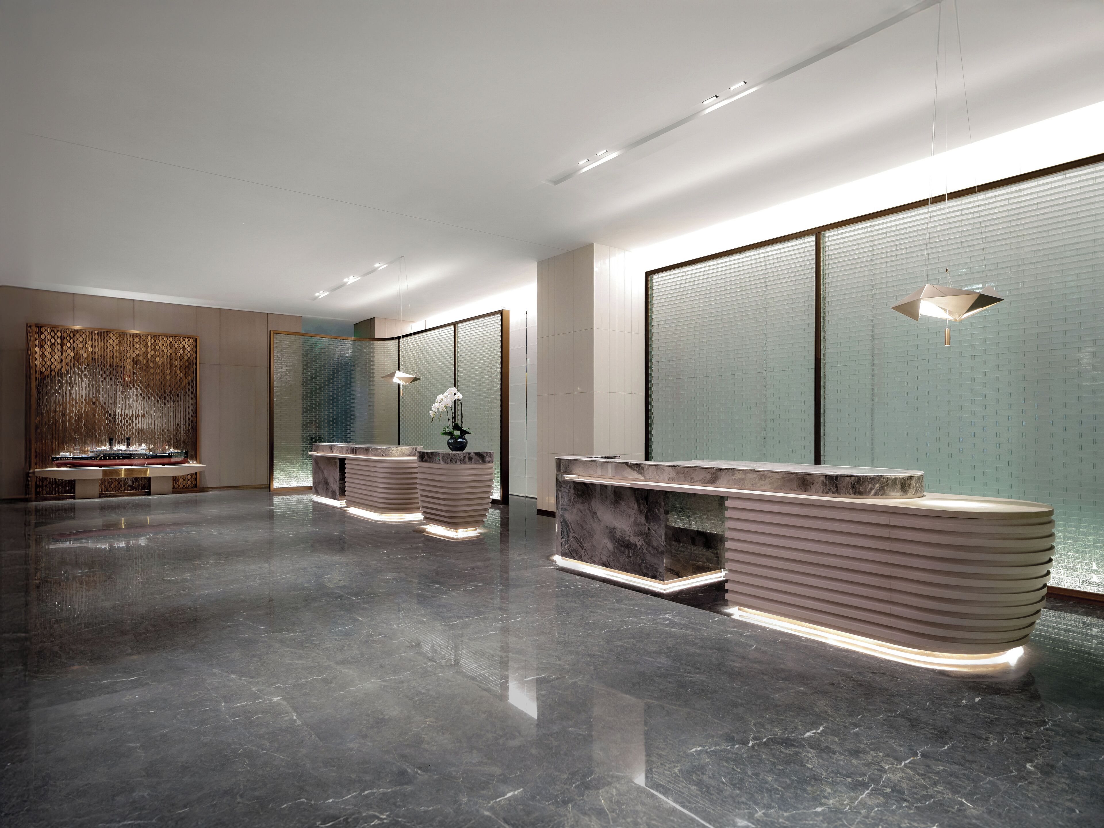 A modern hotel lobby with a reception desk, a decorative ship model, and a large window with blinds.