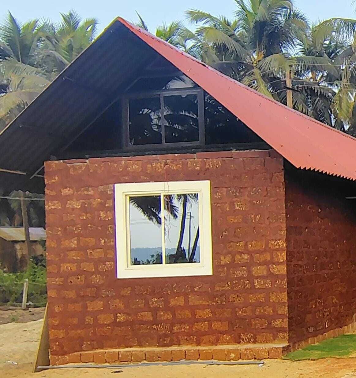 A small brick building with a red roof and a window.