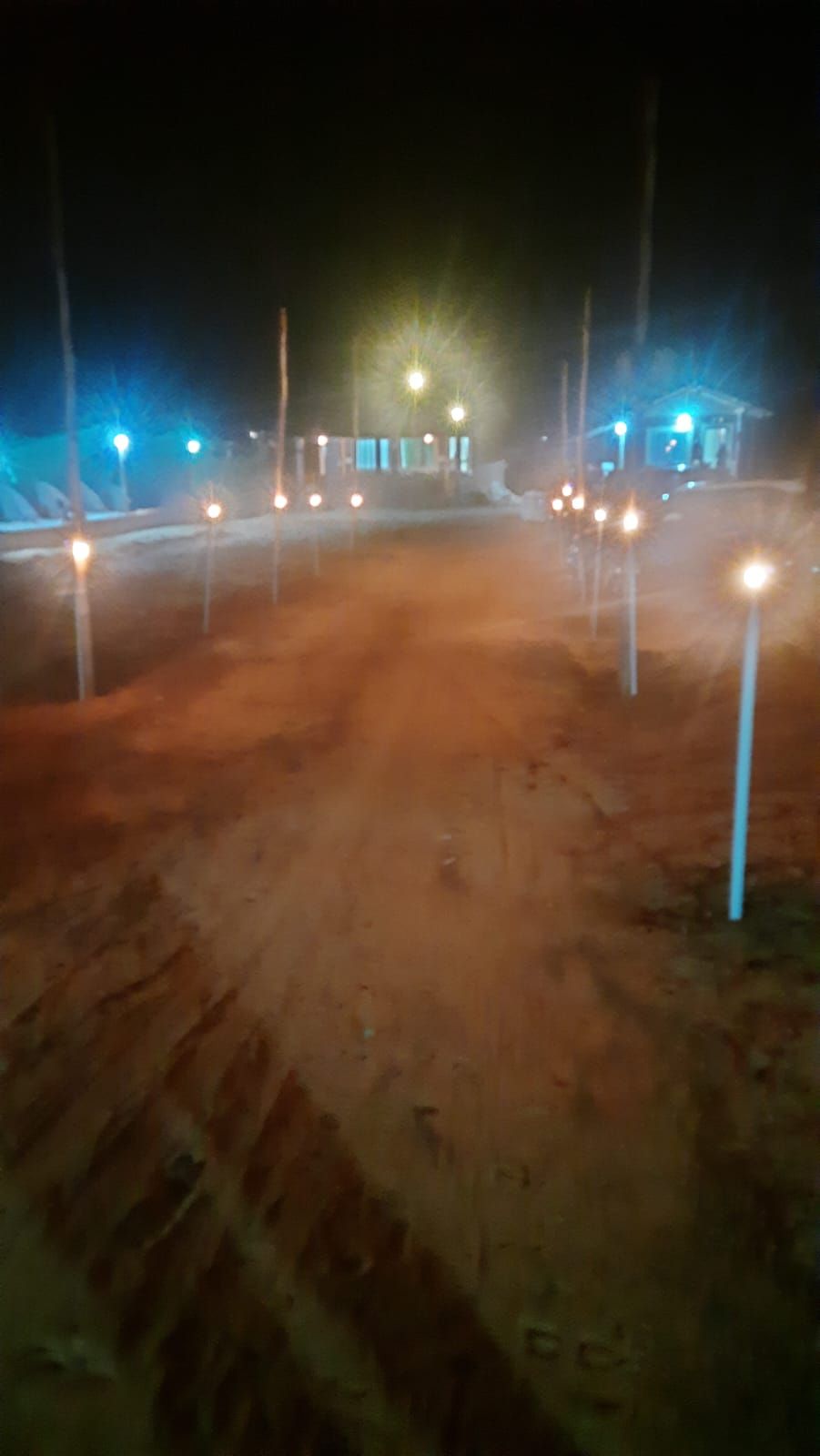 Ein schottriger Pfad führt zu einem Gebäude mit mehreren Lichtern entlang der Seiten.