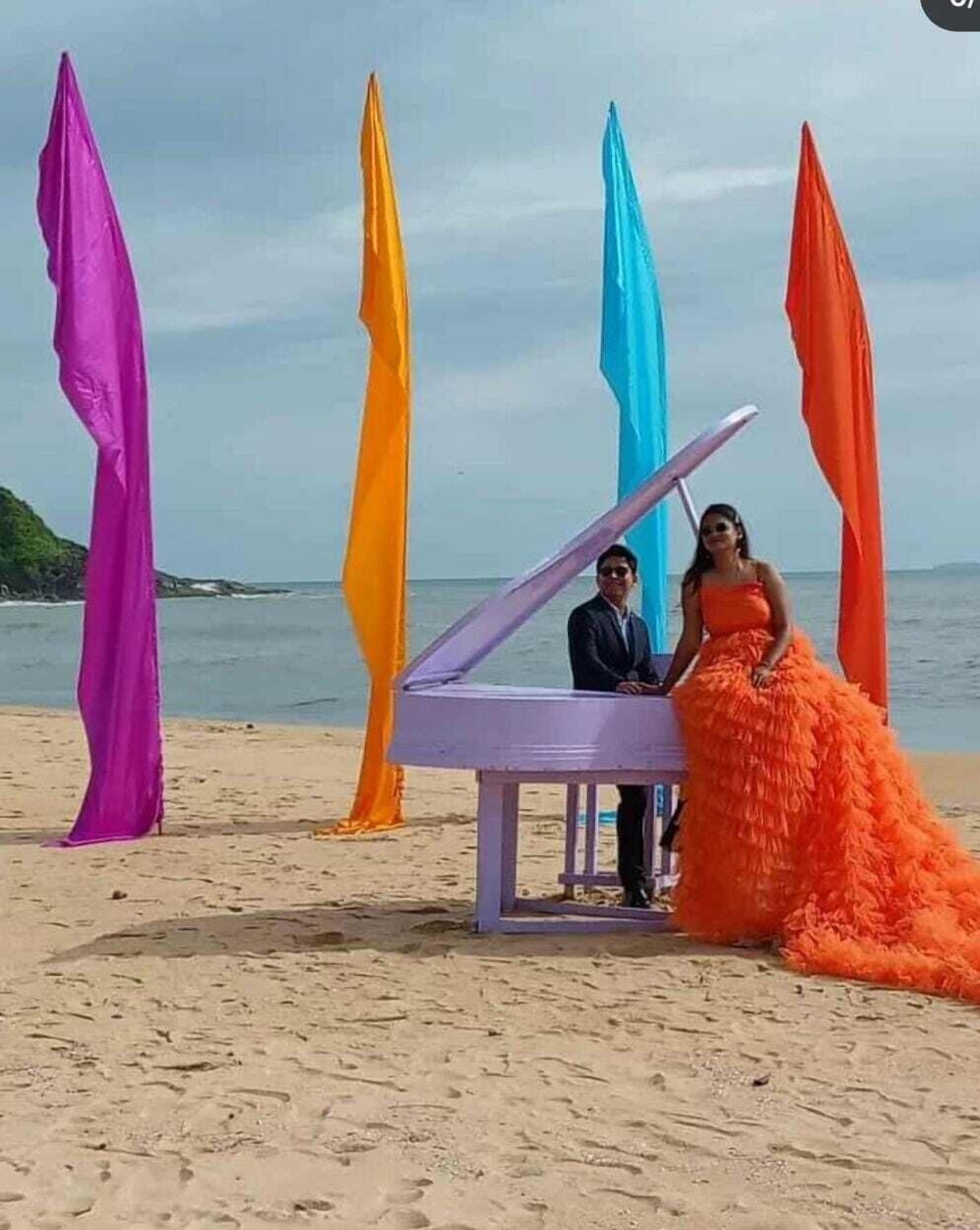 Escena de playa con un piano y estructuras de tela colorida.