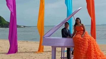 Escena de playa con un piano y estructuras de tela colorida.