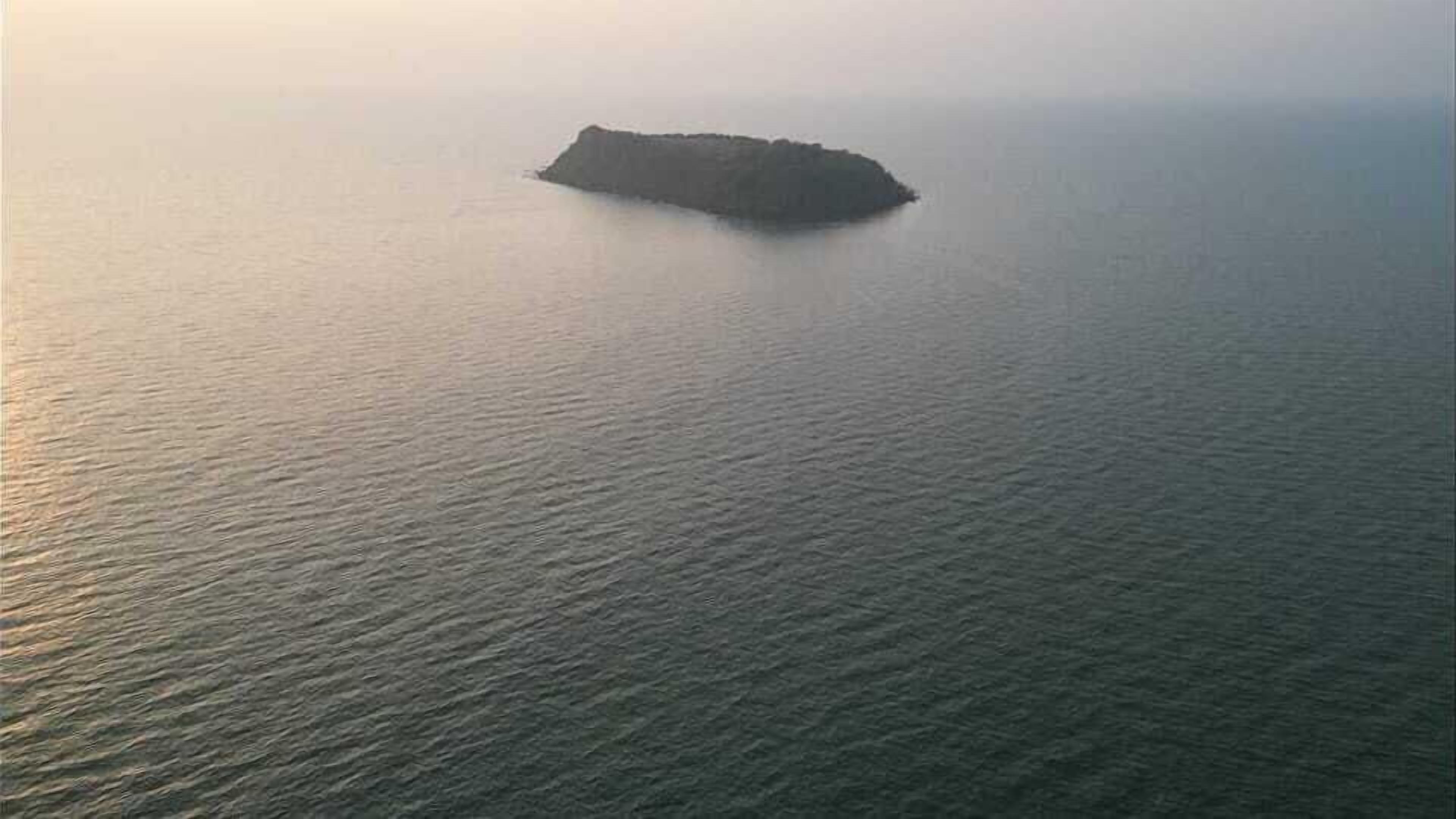 Vista aérea de una pequeña isla rodeada de aguas tranquilas.