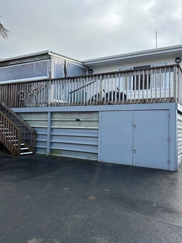 A building with a garage door, a wooden staircase, and a metal fence.
