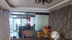 Una sala de estar con un sofá estampado, un ventilador de pie y una lámpara decorativa en el techo.