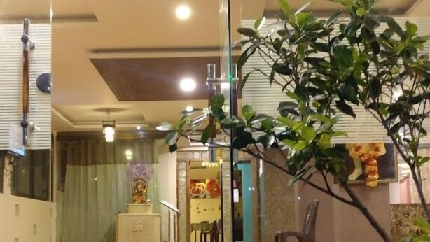 Zona de recepción de un hotel con puerta de vidrio, mostrador de recepción y una estatua al fondo.