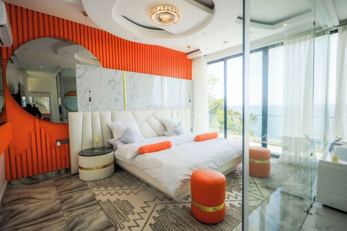 Ein modernes Schlafzimmer mit einem großen Bett, einer Glastrennwand und Blick ins Freie.