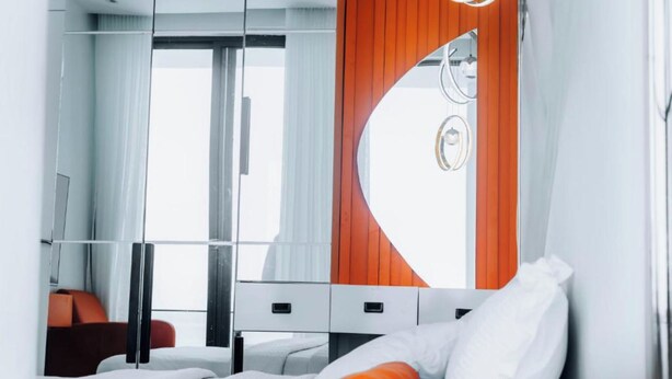 Ein modernes Hotelzimmer mit einem Bett, einem Spiegel und einem Fenster.