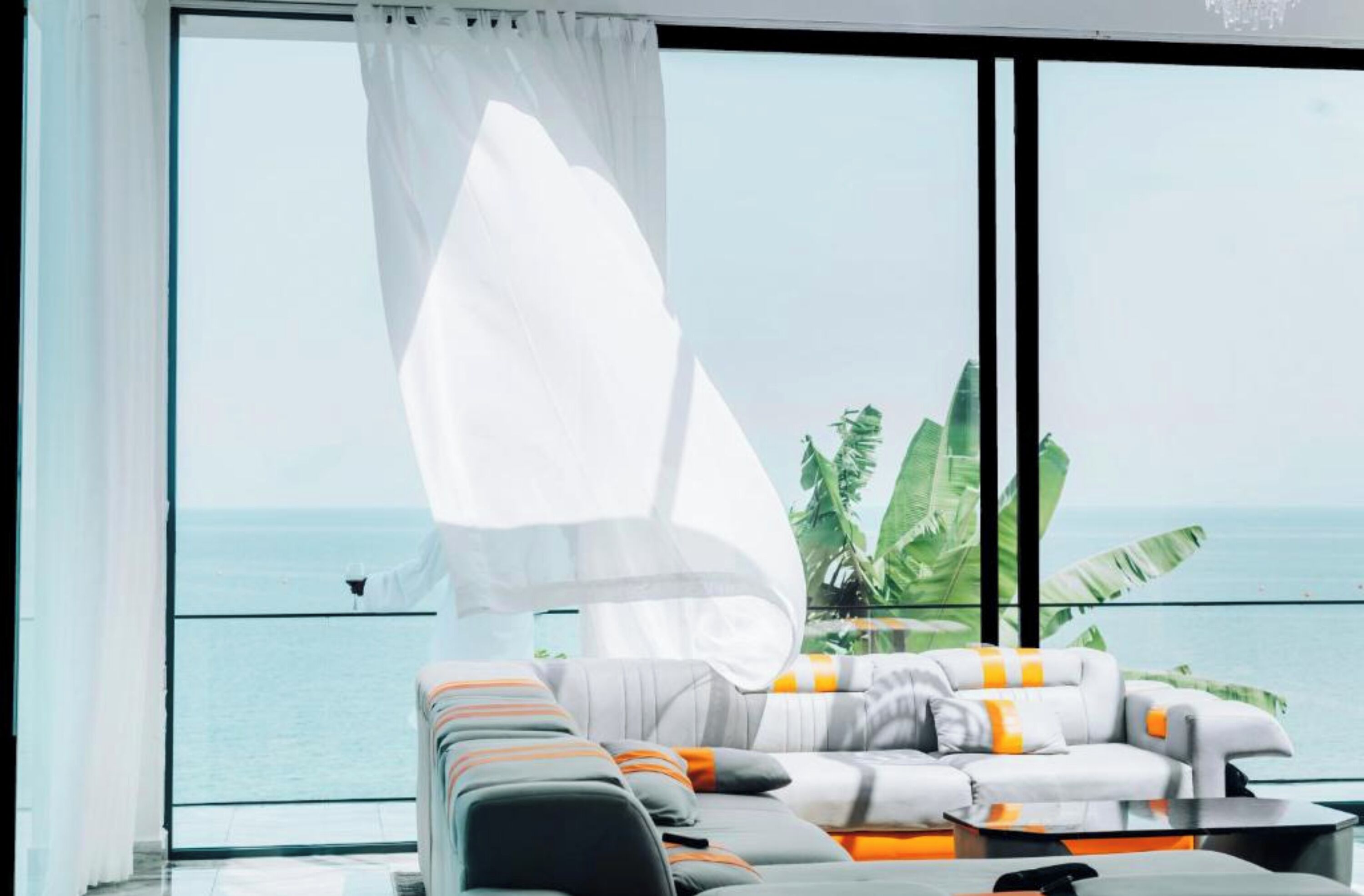Ein modernes Wohnzimmer mit großem Fenster mit Meerblick, ausgestattet mit einer Couch und einem Couchtisch.
