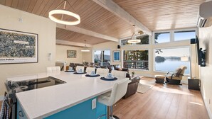A spacious kitchen with a large island, bar stools, and a view of a lake.
