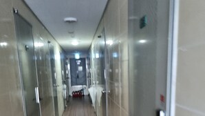 A corridor with mirrored doors, a tiled floor, and a fire extinguisher on the wall. - kinghouse (Gwangju)