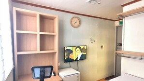 A compact office space with a desk, chair, TV, and shelving unit. - kinghouse (Gwangju)