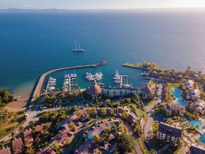A marina with boats docked, a hotel with a pool, and a view of the ocean.