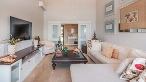 Ein modernes Wohnzimmer mit Flachbildfernseher, weißen Sofas, einem Couchtisch und Dekorationselementen.