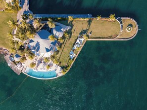 Oversigtsbillede af et resort med en pool, palmer og et cirkulært dækområde.