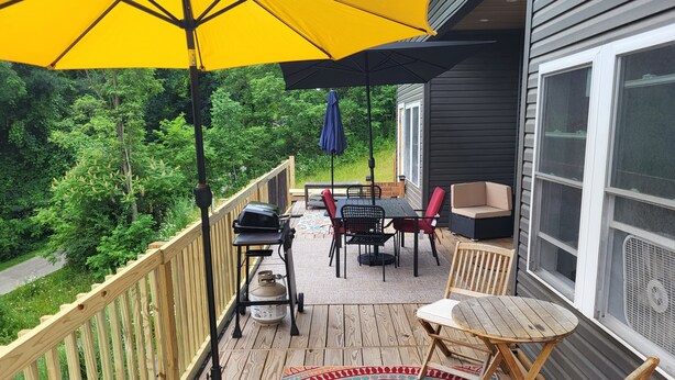 Une terrasse en bois avec une table, des chaises et un parasol jaune.