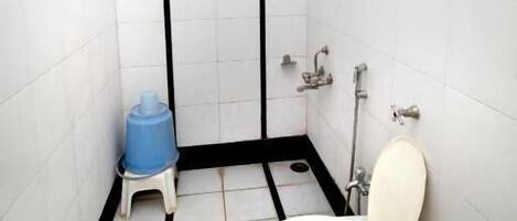 A small, tiled bathroom with a toilet, sink, and shower.