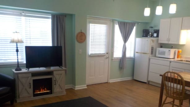 Un espacio habitable compacto con chimenea, televisor, zona de cocina y mesa de comedor.