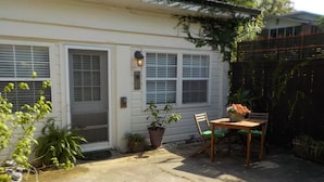 Una casita con un patio, una mesa con sillas y una planta en maceta.