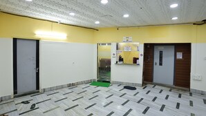 Un vestíbulo de hotel con mostrador de recepción, escritorio de información y zona de espera.