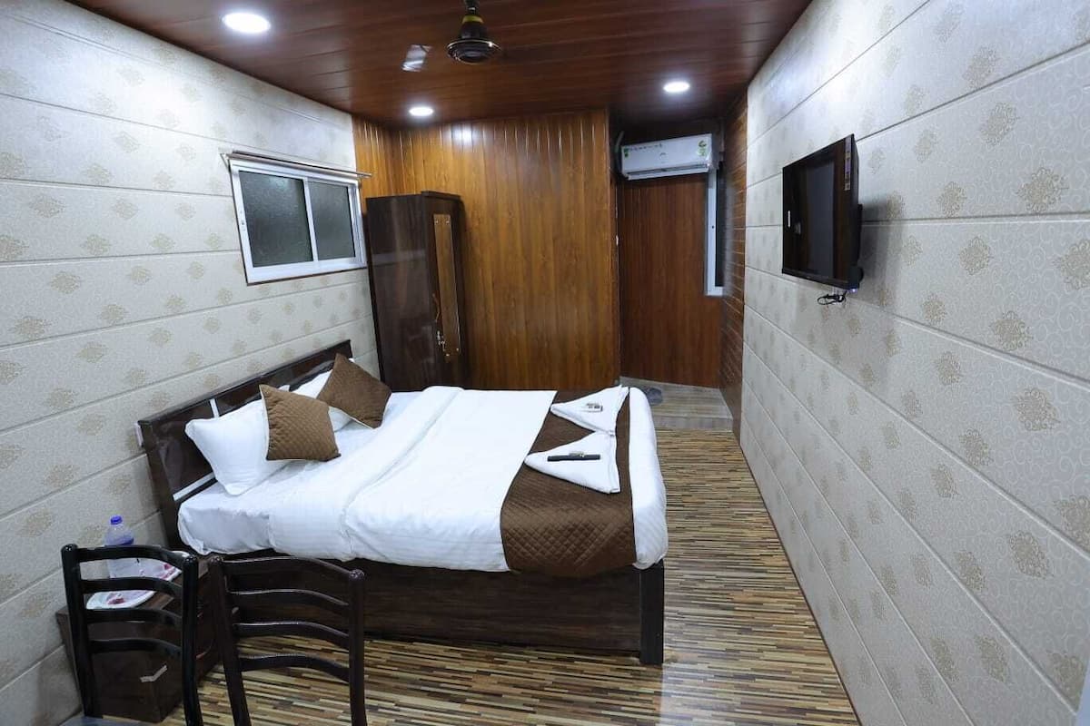A hotel room with a bed, a TV, a wardrobe, and a window.