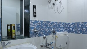 Un baño con un lavamanos blanco, un inodoro y un cabezal de ducha empotrado en la pared.