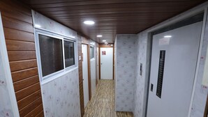Un estrecho pasillo con paneles de madera en las paredes, piso estampado y puertas blancas con un letrero sobre una de ellas.
