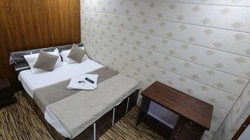 A hotel room with a bed, a bench, a wooden nightstand, and a patterned wall.