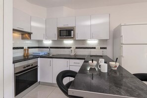 Una cocina moderna con armarios blancos, un microondas, un tostador y un refrigerador.