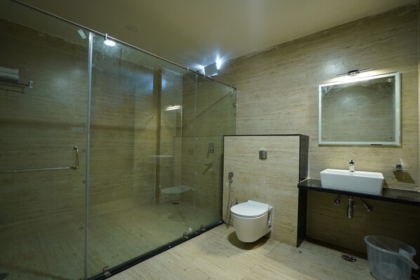 A modern bathroom with a glass-enclosed shower, a white toilet, and a sink with a mirror above it. - HOTEL PSK INN A BOUTIQUE (Chandauli)