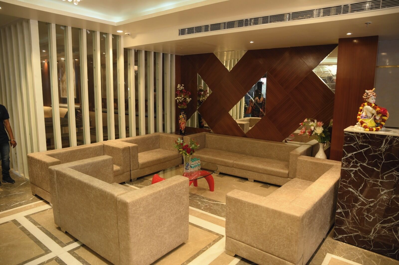 A lobby with beige sofas, a glass coffee table, and a marble reception desk.