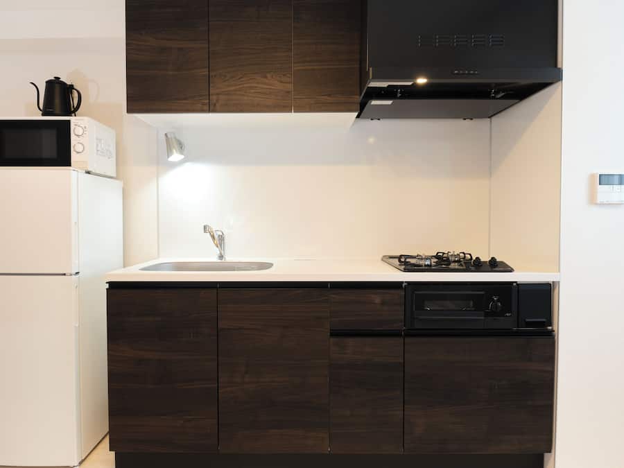 Uma cozinha moderna com frigorífico branco, micro-ondas, pia e fogão.