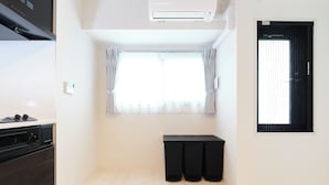 Egy modern konyha sötét színű szekrényekkel, beépített sütővel és áttetsző függönnyel ellátott ablakkal.