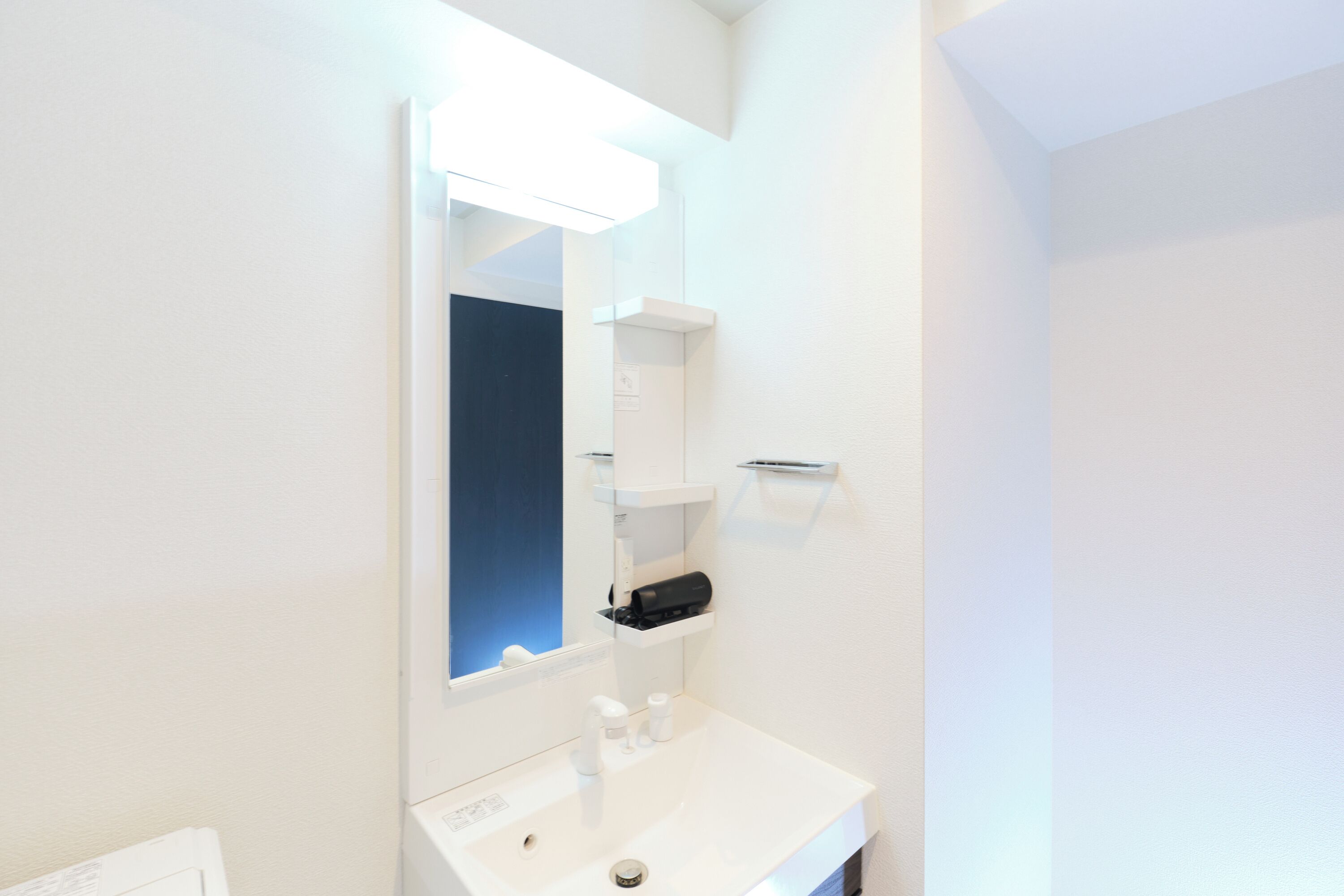 A modern bathroom with a white sink, mirror, and shelves.