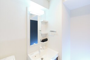 A modern bathroom with a white sink, mirror, and shelves. - Metro Gate Morishita (Tokyo)