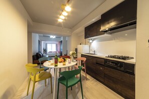 Una cocina moderna con comedor, que incluye una mesa redonda con sillas, un refrigerador, una estufa y armarios de madera.