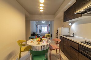 Una cocina funcional con electrodomésticos modernos, un comedor con sillas de colores y vistas a una sala de estar.