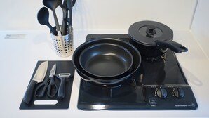 A kitchen with a stove, a frying pan, a pot, a spatula, a ladle, a pair of scissors, and a knife on a cutting board. - Metro Gate Morishita (Tokyo)