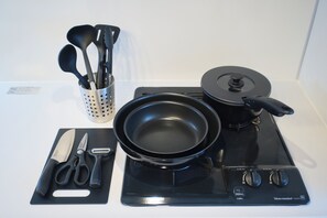 A kitchen with a stove, a frying pan, a pot, a spatula, a ladle, a pair of scissors, and a knife on a cutting board. - Metro Gate Morishita (Tokyo)