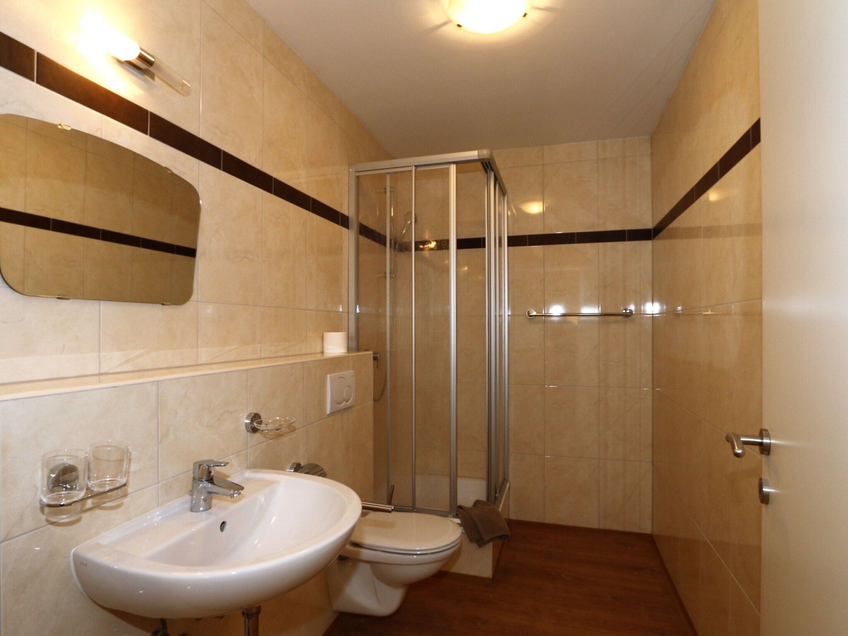 Un baño con lavamanos, inodoro y cabina de ducha de vidrio.