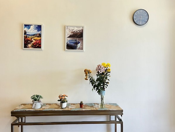 Una habitación con una mesa mostrando varias plantas en macetas y dos cuadros en la pared.