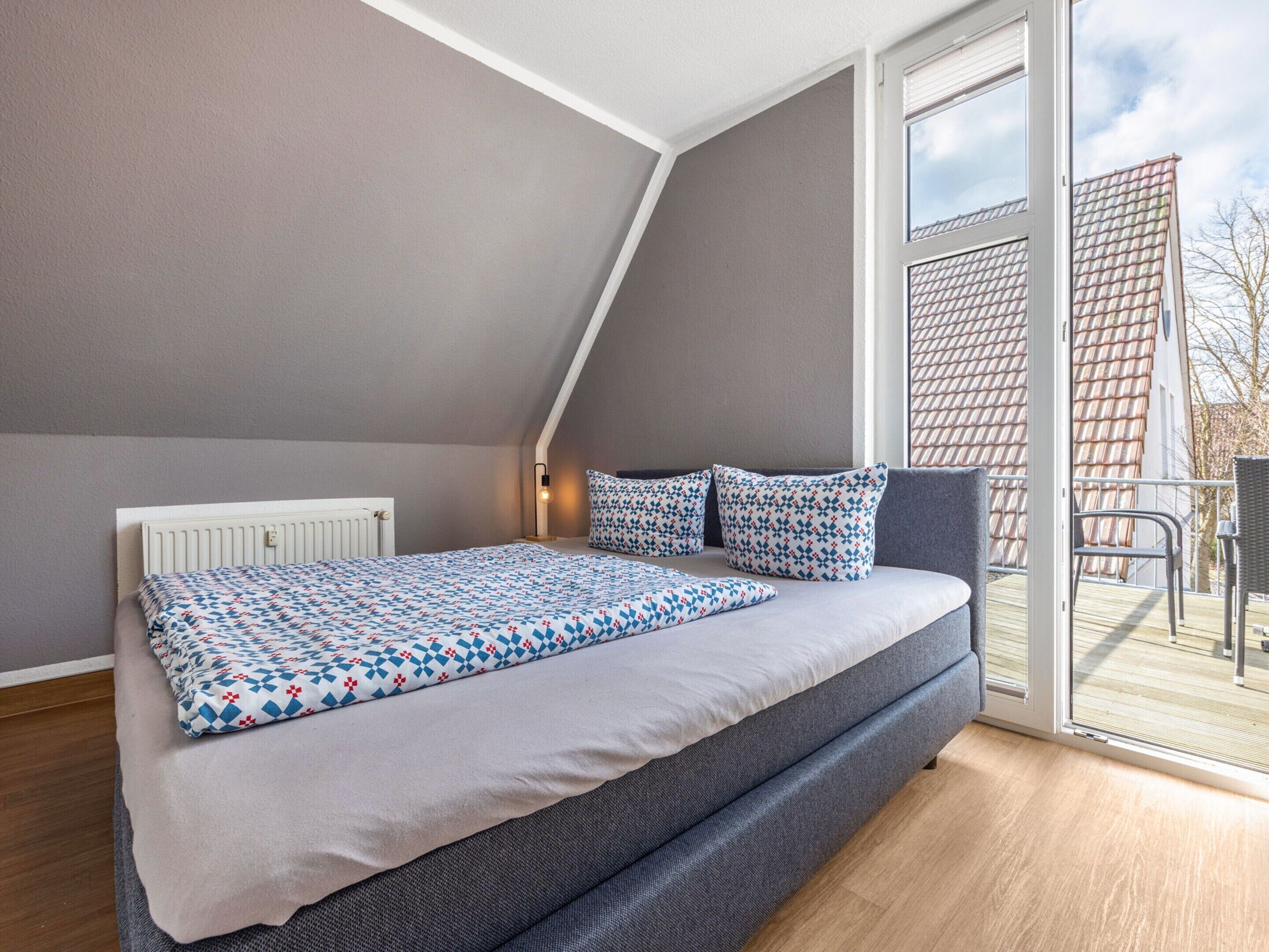A bedroom with a bed, a radiator, a window, and a view of a building outside.
