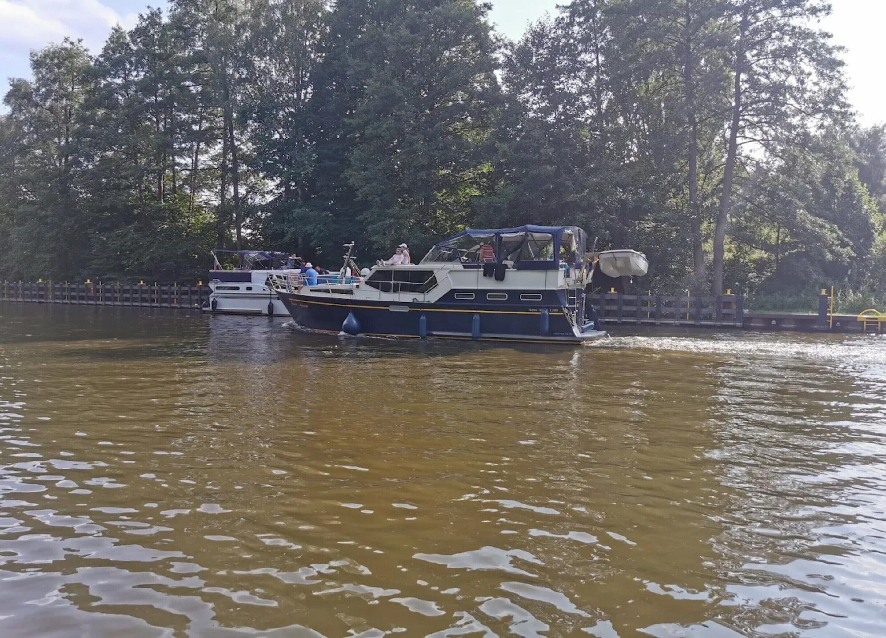 Ein Boot mit Passagieren auf einem Fluss, umgeben von Bäumen.