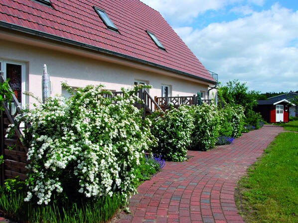 A house with a red roof, white exterior walls, and a brick pathway leading to the entrance.