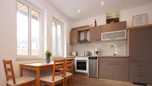Une cuisine moderne avec des chaises en bois, une table à manger, un four encastré, un lave-vaisselle et un réfrigérateur.