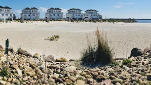 Ein Strandhotel mit mehreren weißen Gebäuden, einem Sandstrand und einem felsigen Vordergrund.