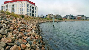 Ein Anwesen am Wasser mit felsigem Ufer, einem Gebäude mit rotem Dach und moderner Architektur.