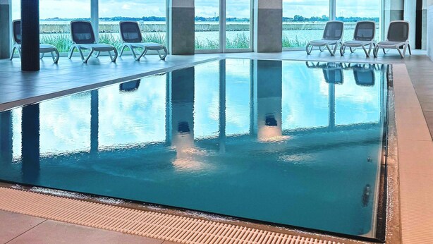 Ein Innenpool mit freiem Blick ins Freie, umgeben von Liegestühlen.