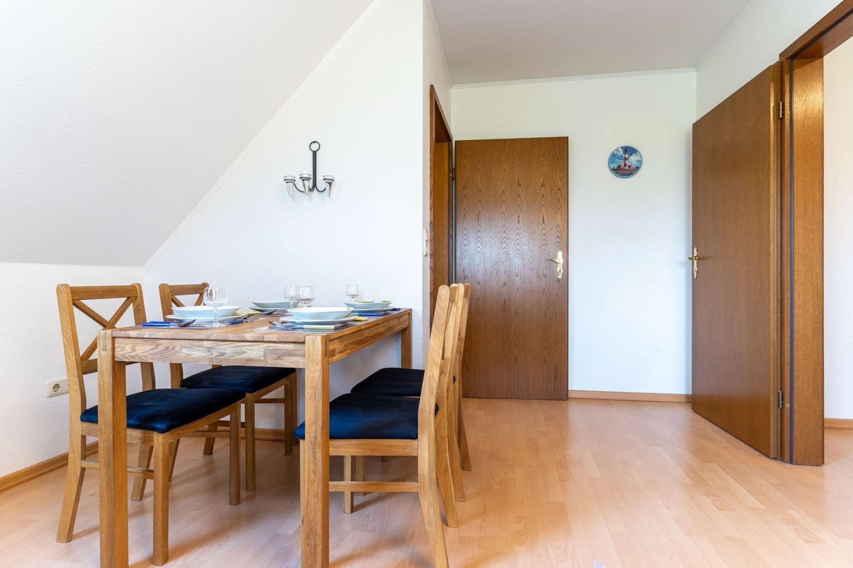 A dining area with a wooden table and chairs, a chandelier, and a door with a circular decoration.